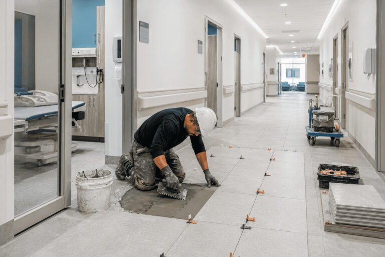 Commercial tile contractor installing slip-resistant ceramic flooring in a healthcare facility corridor in {city}
